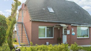 A two-story brick house with a tiled roof, a small window, and a door. - Moderne Ferienwohnung in Meeresnähe in Tarnewitz (Boltenhagen (Ostseebad))