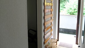 A hallway with a wooden rack holding keys and a small wooden bench with a bottle on it.