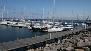 A marina with multiple sailboats docked at wooden piers.