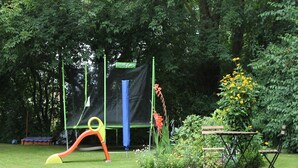 A playground with a slide, a climbing structure, and a bench.