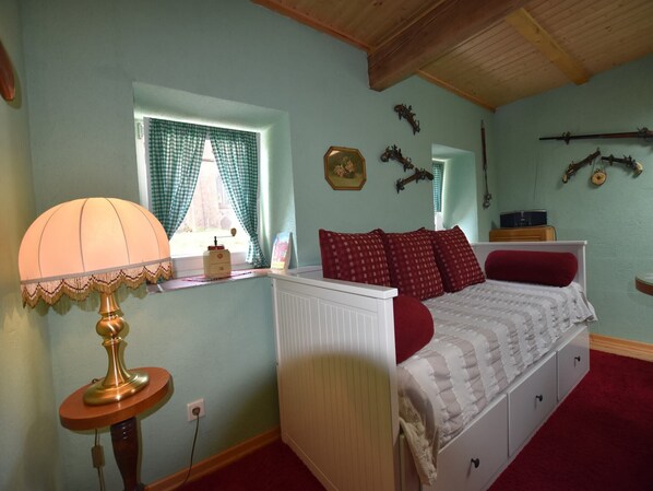 A bedroom with a bed, a lamp, a window with curtains, and wall decorations.