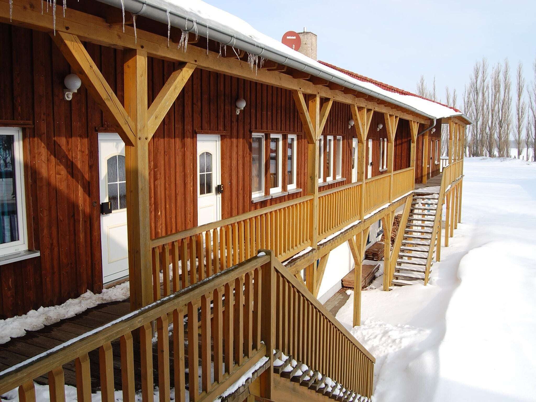 A wooden cabin with a covered porch and a snow-covered landscape.