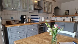 A kitchen with grey cabinets, a wooden countertop, a coffee maker, and a vase with flowers on the table. - Schicke Ferienwohnung in der Nähe der Ostseeküste (Gerdshagen)