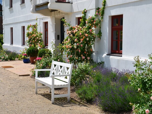 Sit and unwind in a serene garden setting, surrounded by lush climbing roses and vibrant flowering plants.