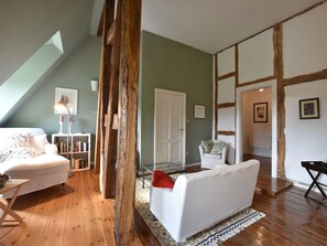 Relax in a cozy space with a plush sofa, armchair, and bookshelf, perfect for unwinding.