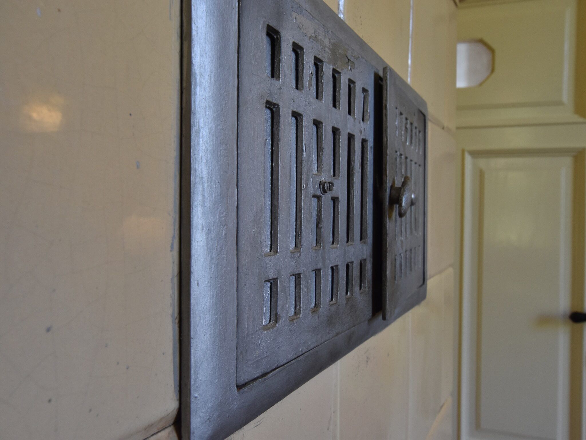 A metal vent with a keyhole and a door knob, mounted on a wall.