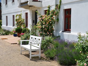 A white bench in front of a building with a white facade and red window frames. - Wohnung in Satow mit Garten (Gerdshagen)