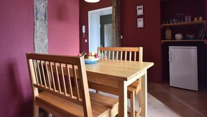 Un'area pranzo con un tavolo e sedie in legno, una ciotola di frutta e un frigorifero bianco sullo sfondo.