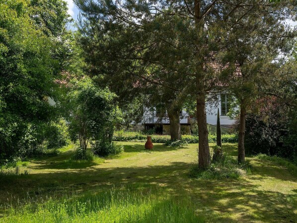 A garden with a pathway leading to a building, surrounded by trees and greenery.