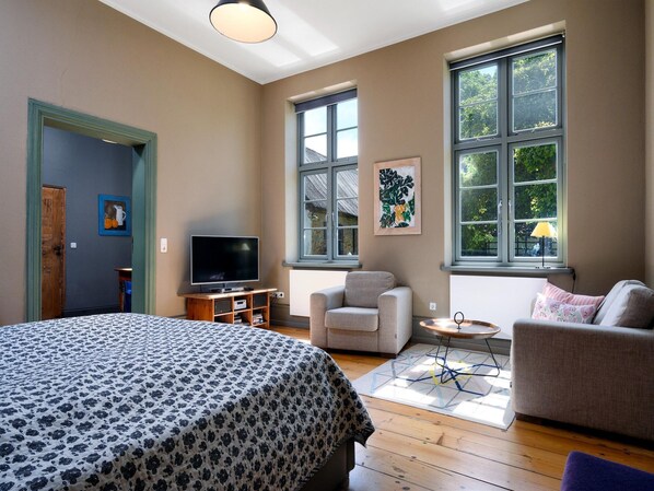 A bedroom with a bed, a television, a chair, and a sofa.