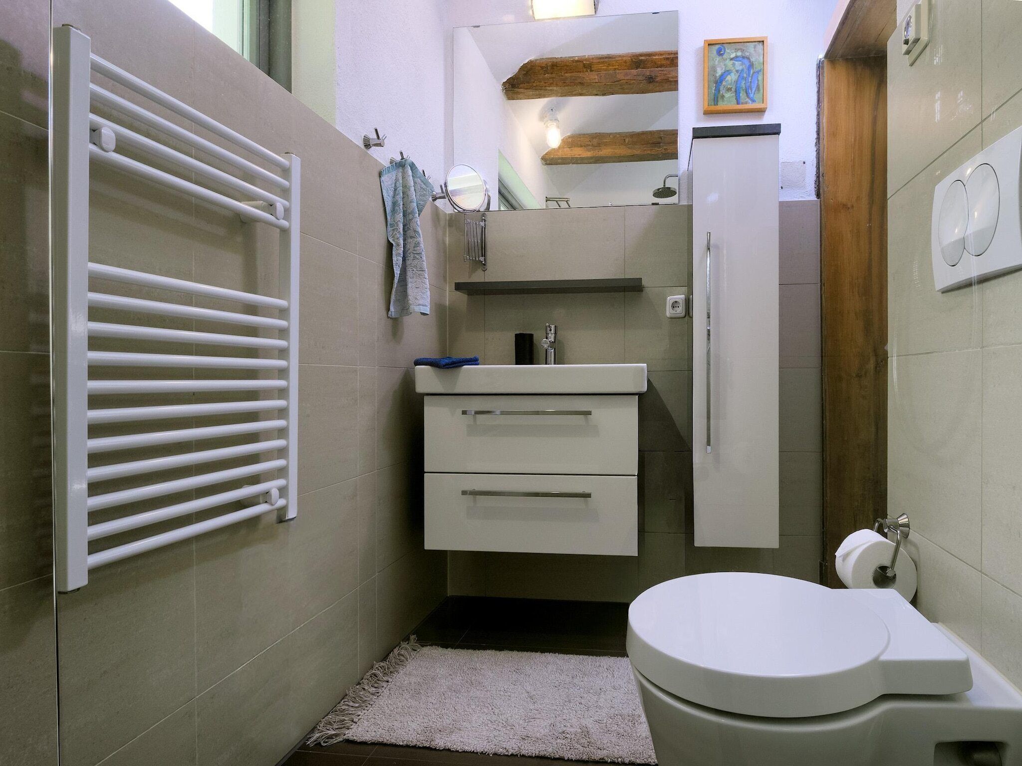 A compact bathroom with a white toilet, a sink with a mirror, and a towel rack.