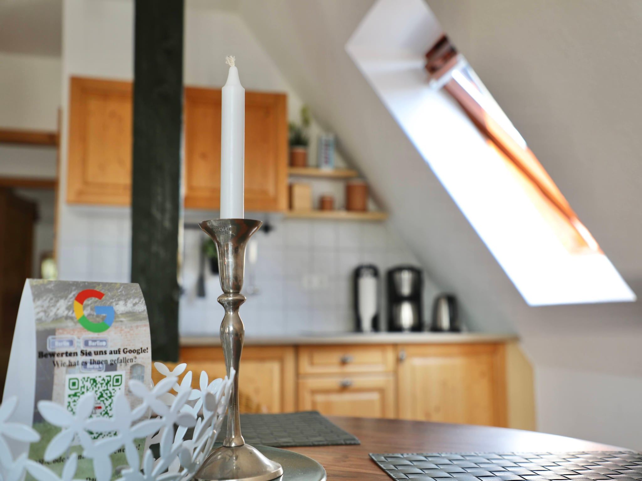 A candle in a silver holder on a table with a QR code and a white decorative item.