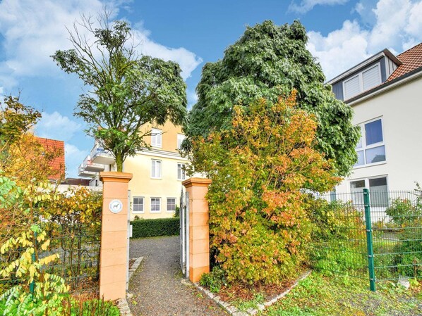 A residential area with a pathway leading to a building with a yellow facade and multiple windows. - Modernes Appartement mit Terrasse auf Rügen (Wiek auf Rügen)