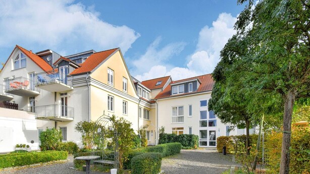 A residential area with multi-story buildings, a gravel courtyard, and well-maintained greenery. - Modernes Appartement mit Terrasse auf Rügen (Wiek auf Rügen)