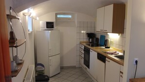 A compact kitchen with white cabinets, a microwave, a coffee maker, and a dishwasher. - Wohnung in Weibig mit Garten (Struppen)