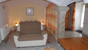 A cozy living room with a sofa, a wooden table, and a patterned curtain. - Wohnung in Weibig mit Garten (Struppen)