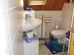 A small bathroom with a white sink, toilet, and a blue mat on the floor. - Wohnung in Lichtenhain beim Böhmischen Park (Lichtenhain)
