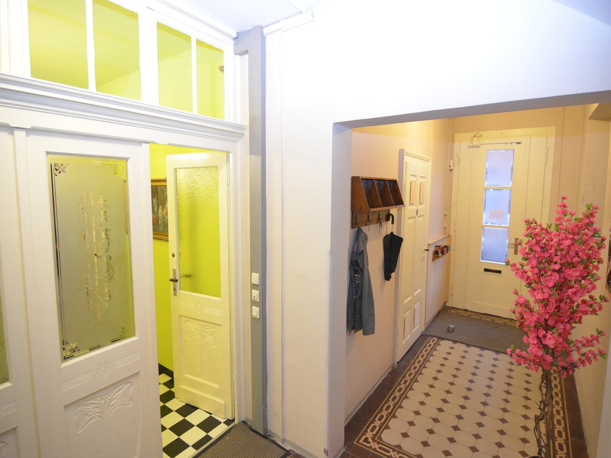 A hallway with a checkered floor, a door with frosted glass panels, and a wall-mounted coat rack.