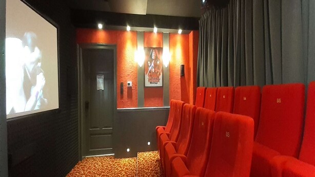 En biograf med røde sæder, et lærred og en Star Wars plakat på væggen.