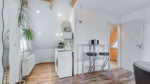 Une cuisine compacte équipée d’un réfrigérateur, d’un four à micro-ondes et d’un petit coin repas avec des tabourets.