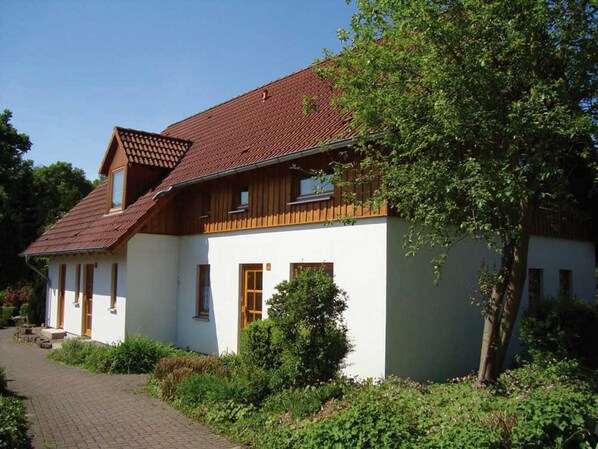 A two-story house with a sloped roof, white exterior walls, and wooden window frames. - Holiday Home in Germany with Garden Terrace (Brakel-Bellersen)