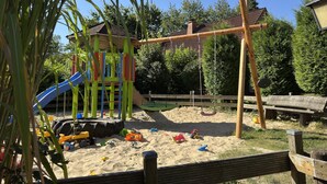 A playground with a slide, swings, and a sandpit.
