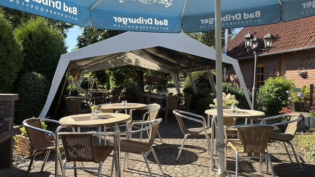 An outdoor seating area with tables and chairs under a large tent with a logo. - Holiday apartment in the Teutoburg Forest (Brakel-Bellersen)