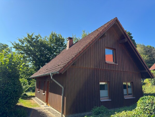 A wooden house with a sloped roof, a chimney, and a small window. - Holiday apartment in the Teutoburg Forest (Brakel-Bellersen)