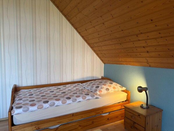 Un lit simple avec une couvre-lit à pois dans une pièce dont le plafond et les murs sont en bois.