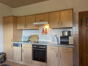 A compact kitchen with wooden cabinets, a Bosch oven, a microwave, and a coffee maker.