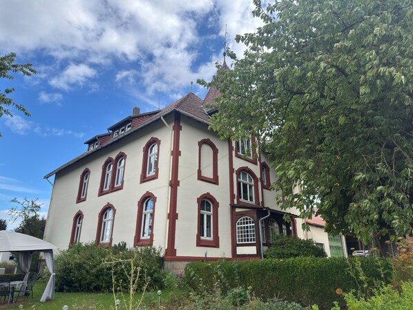 A two-story building with a symmetrical facade, multiple windows, and a red-tiled roof.
