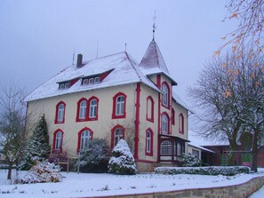 A large, two-story building with a steeply pitched roof and a prominent tower.