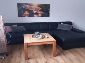 A living room with a wooden coffee table, a black sofa, and a painting on the wall. - Wohnung in Stormbruch nahe dem Skigebiet (Diemelsee-Stormbruch)
