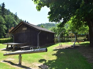 Une grange en bois rustique, avec une table de pique-nique et une balançoire.
