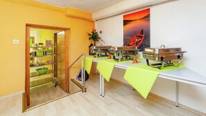 A buffet setup with multiple serving stations, a wooden staircase, and a painting of a sunset on the wall. - hundefreundliches Gruppenhaus in Hessen mit Garten (Bad Zwesten-Wenzigerode)