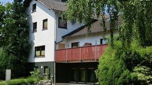 A two-story building with a balcony, surrounded by greenery. - hundefreundliches Gruppenhaus in Hessen mit Garten (Bad Zwesten-Wenzigerode)