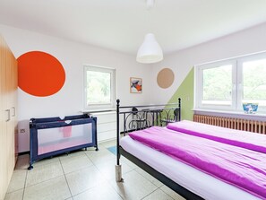 Ein Schlafzimmer mit einem Bett, einem Babybett und einer Heizung.