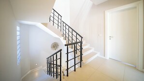 A staircase with black railings, a white door, and a window with a geometric pattern.