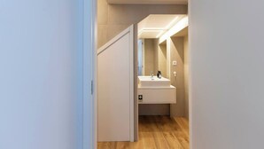 Ein modernes Badezimmer mit einem weißen Waschtisch, einem Spiegel und einer Leuchte über dem Waschbecken.