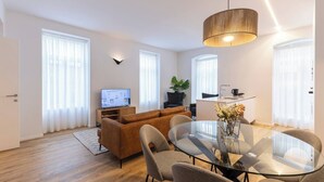 Ein modernes Wohnzimmer mit einer Couch, einem Glastisch und einem Fernseher.