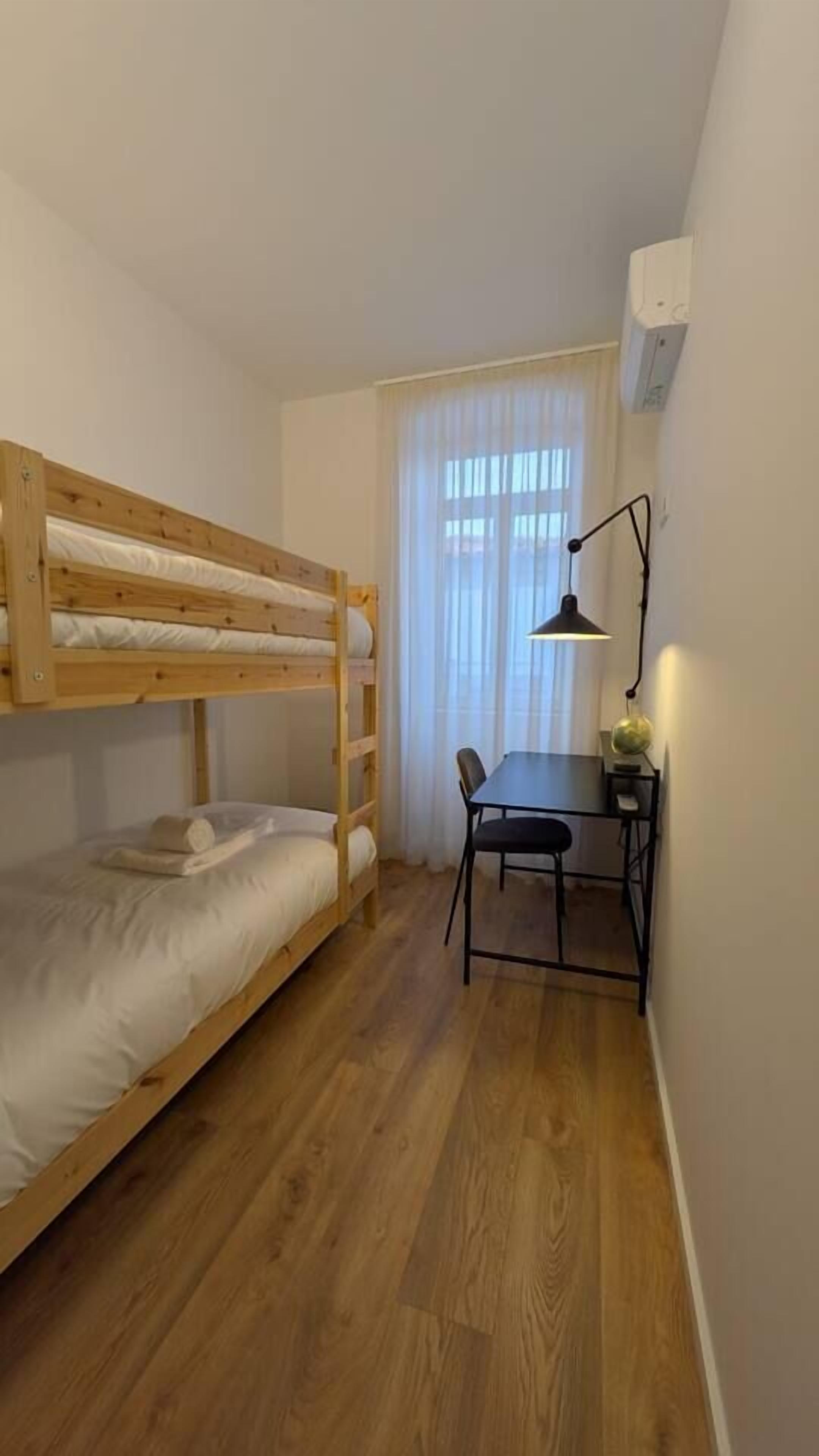 Una habitación pequeña y funcional con una cama litera, un escritorio y una silla.
