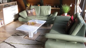 Een gezellige woonkamer met een groene bank, een bijzettafeltje en een houten plafond.