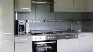A modern kitchen with a built-in oven, a coffee maker, and a stainless steel sink. - Holiday Home in Germany with Scenic Nature (Ronshausen)