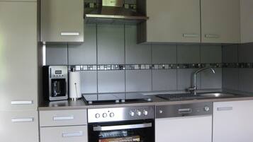 Eine moderne Küche mit Backofen, Kaffeemaschine und Spüle aus Edelstahl.