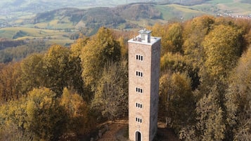 Una torre in pietra con tetto piano, circondata da foglie autunnali.