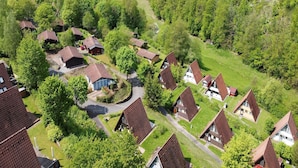 A residential area with houses featuring sloped roofs, surrounded by lush greenery and a hilly landscape. - Holiday Home in Germany with Scenic Nature (Ronshausen)