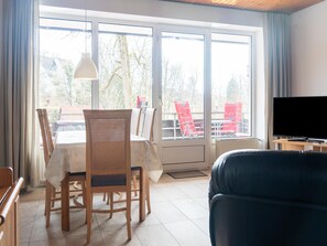A living room with a dining area, a television, and large windows. - Familienwohnung Bergfreunde (St.  Andreasberg)