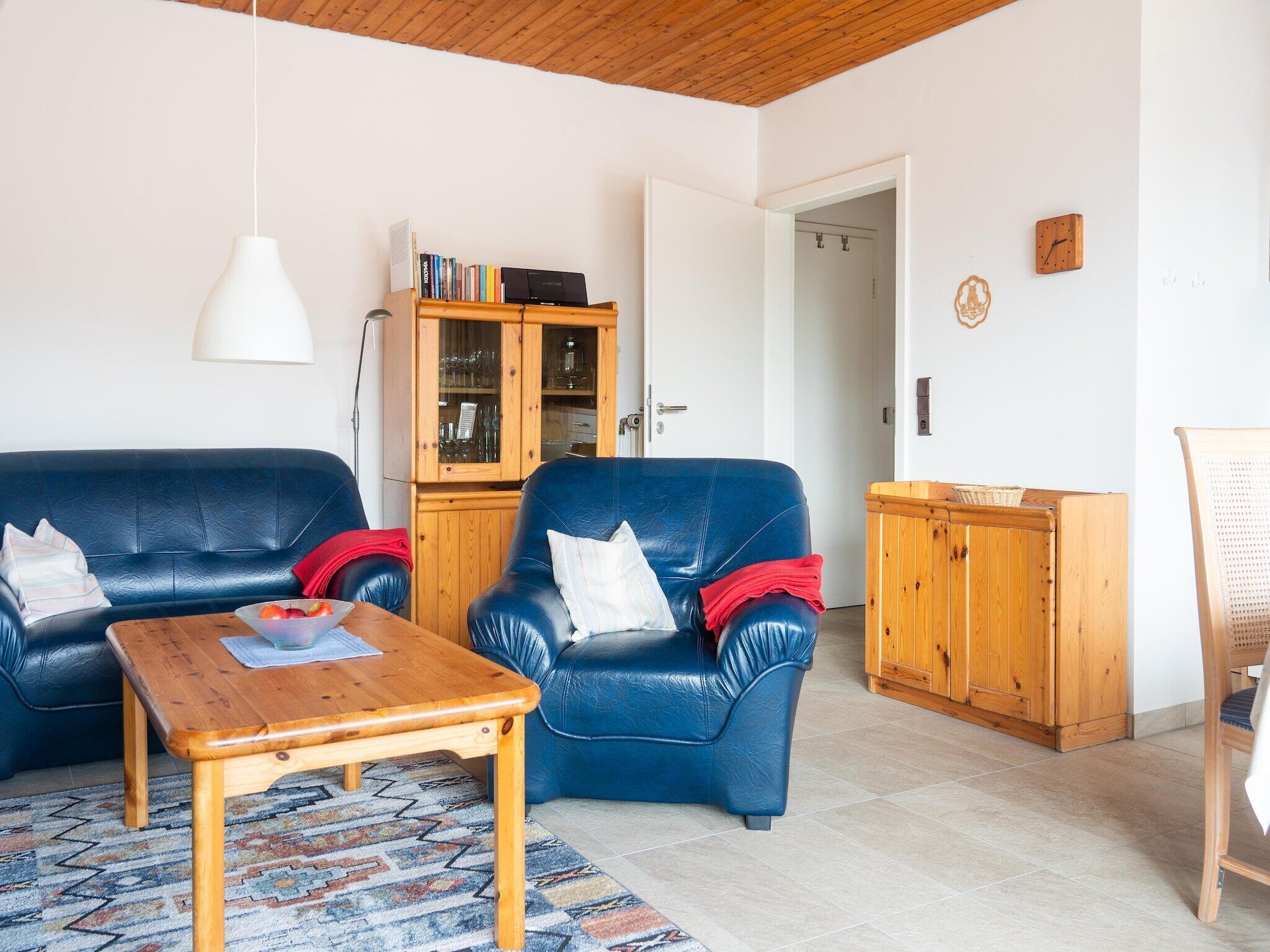 Ein Wohnzimmer mit einem blauen Ledersofa, einem Holztisch und einem Schrank.