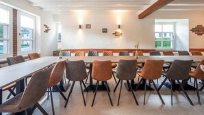 A conference room with a long table, multiple chairs, and a brick accent wall. - Holiday home with sauna in the Eifel National Park (Schleiden)