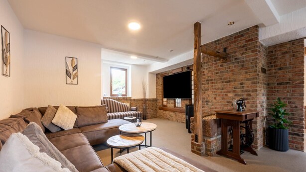 A modern living room with a sectional sofa, a round coffee table, and a fireplace. - Holiday home with sauna in the Eifel National Park (Schleiden)